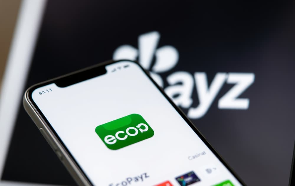 Mobiltelefon med Ecopayz-appen åpen foran et casino på skjermen